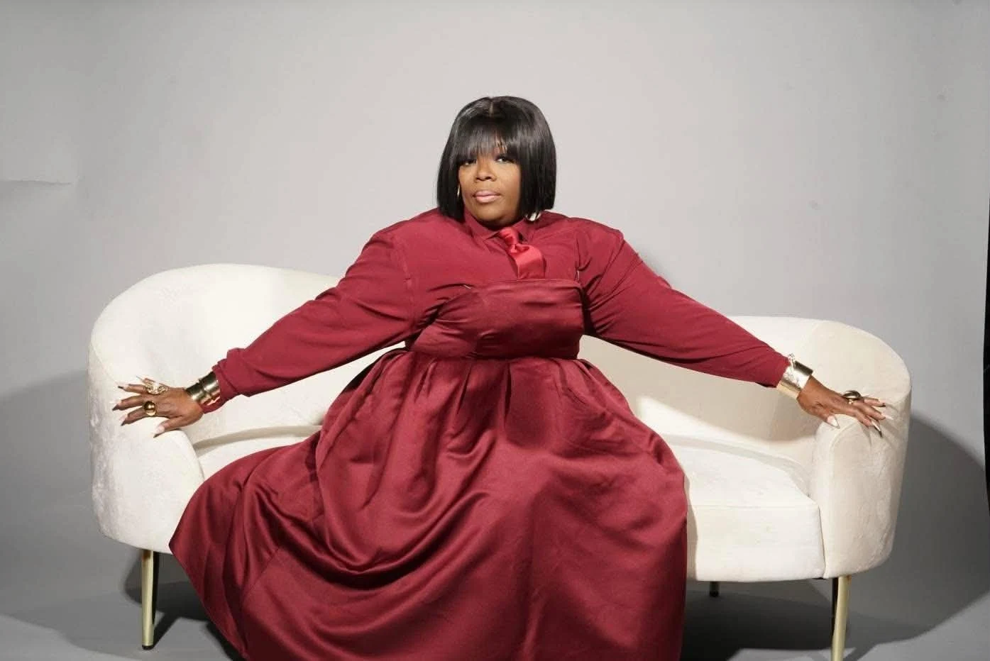 Amelia seated on an ivory sofa in her burgundy dress